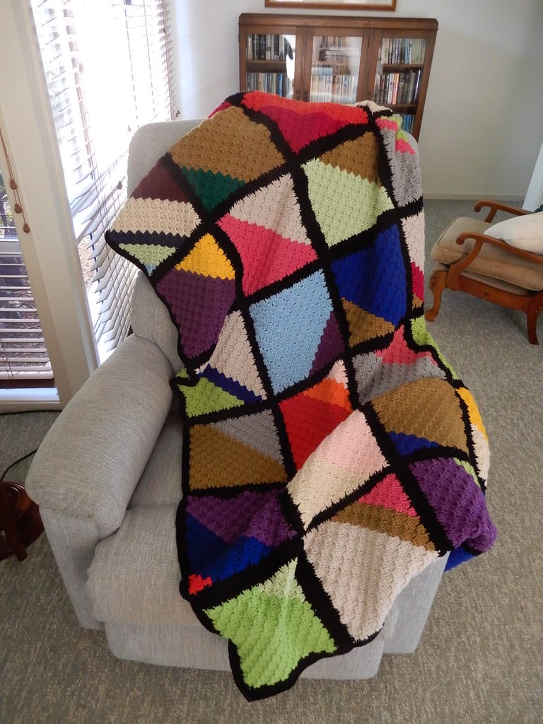 Corner to corner crochet blanket in colorful blocks outlined in black, an example of how to crochet C2C