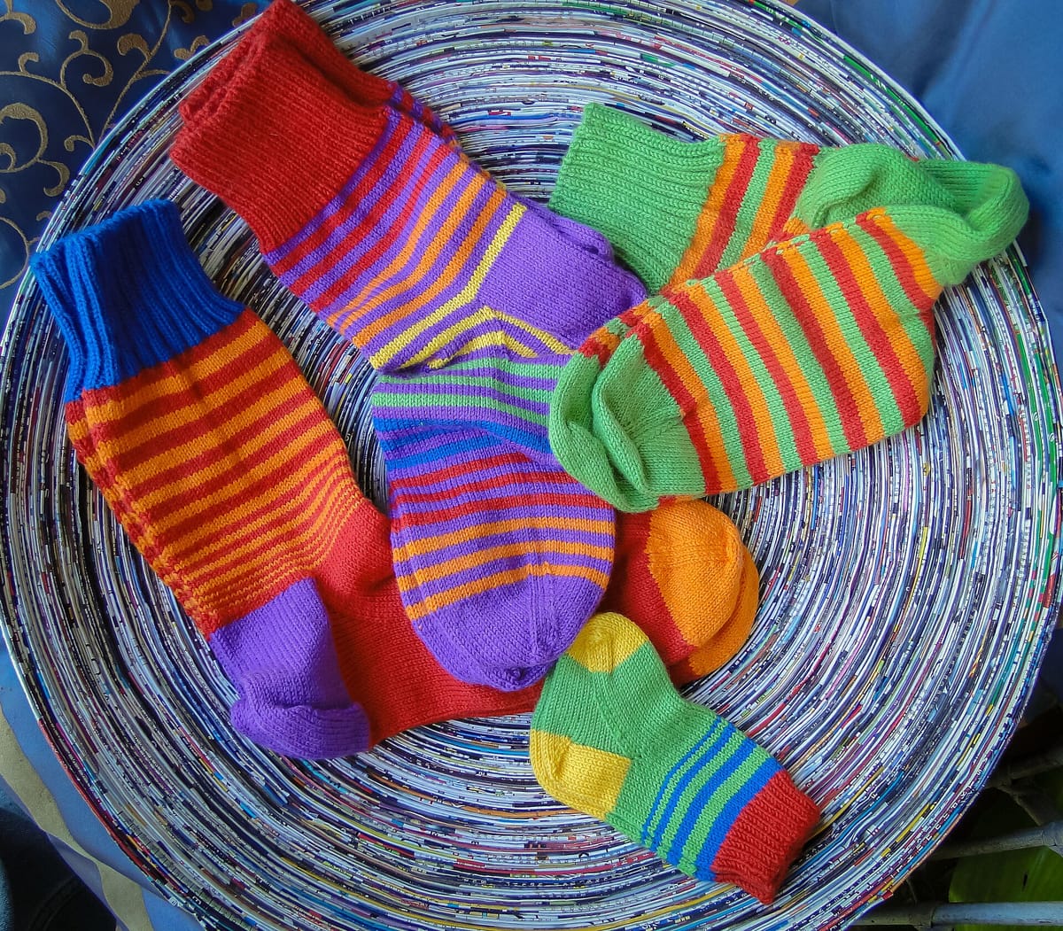 Brightly colored hand-knitted wool socks in a basket, the kind of pair you make when you knit socks